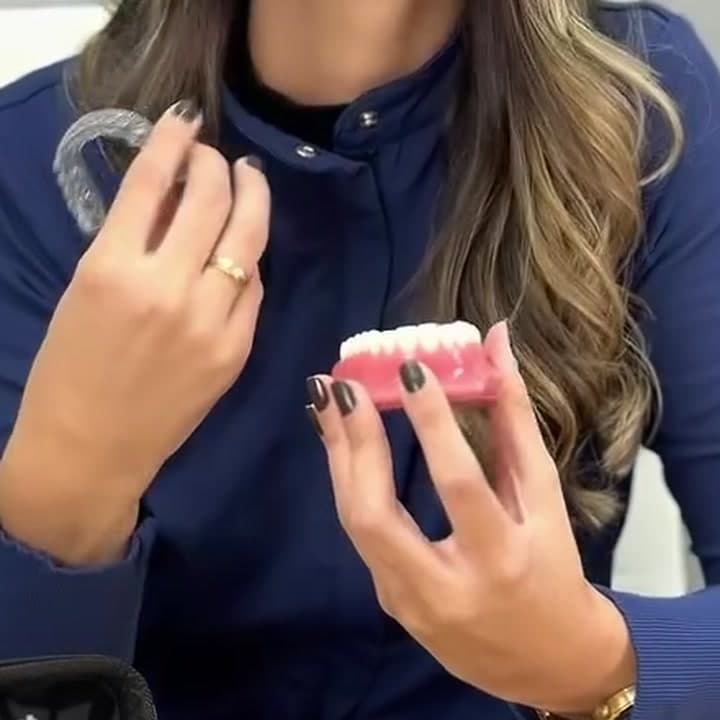 Dentista segurando um alinhador transparente e um modelo da arcada