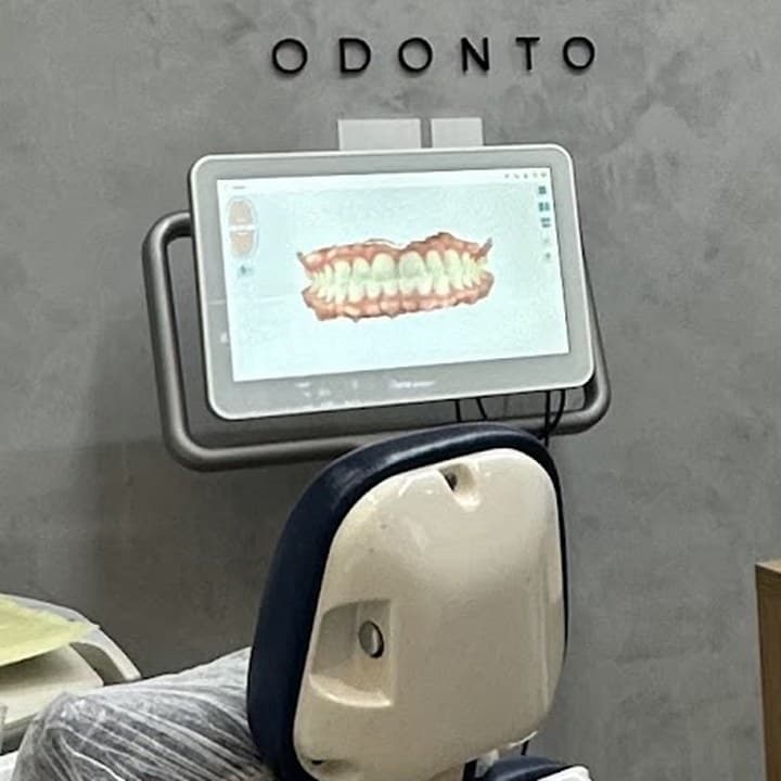 Escâner intraoral do consultório mostrando a arcada escaneada na tela, com o letreiro Odonto na parede